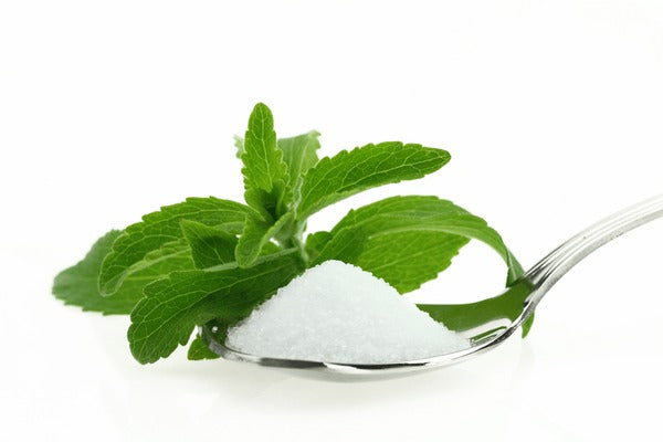 Stevia Leaf behind a teaspoon with sugar